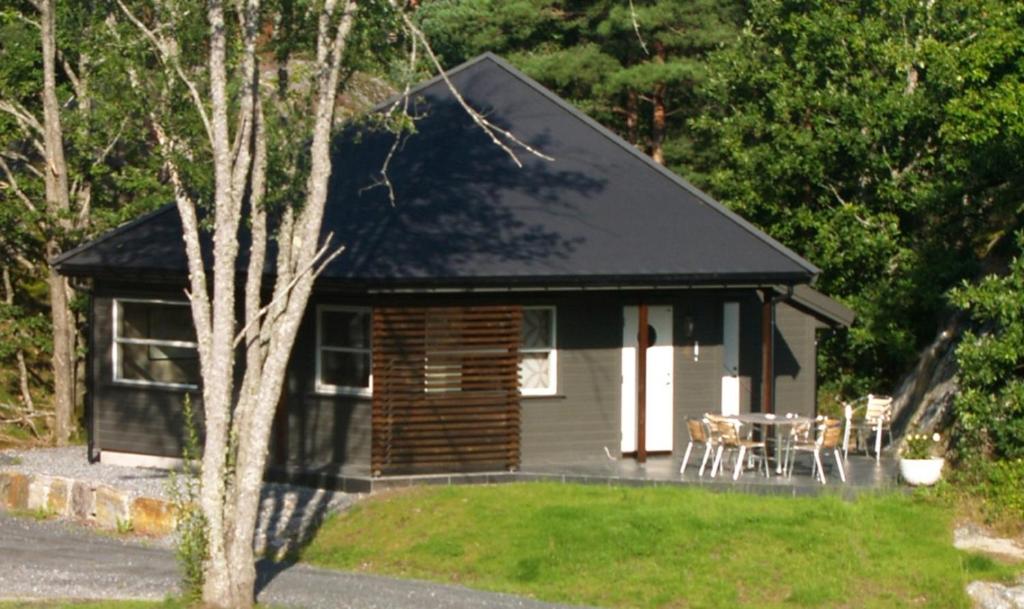 a log cabin with a table and chairs in a yard at Risør Gjestehus in Risør