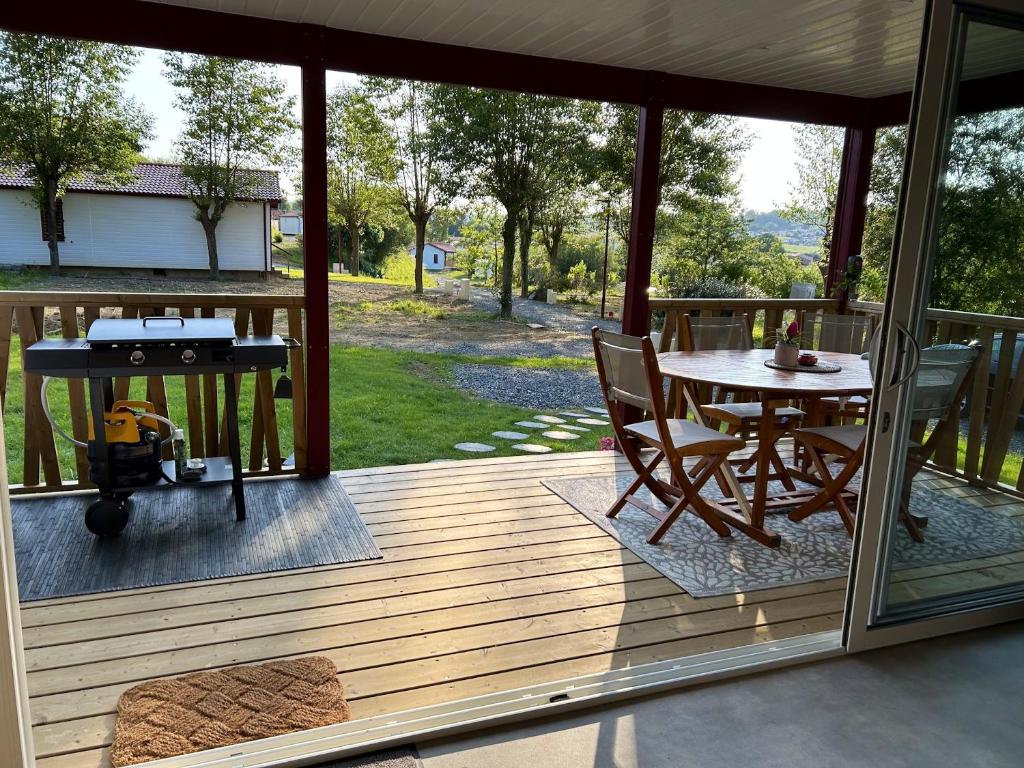 eine abgeschirmte Veranda mit einem Tisch und einem Grill in der Unterkunft Chalet de 3 chambres avec piscine partagee jacuzzi et jardin amenage a Hasparren in Hasparren