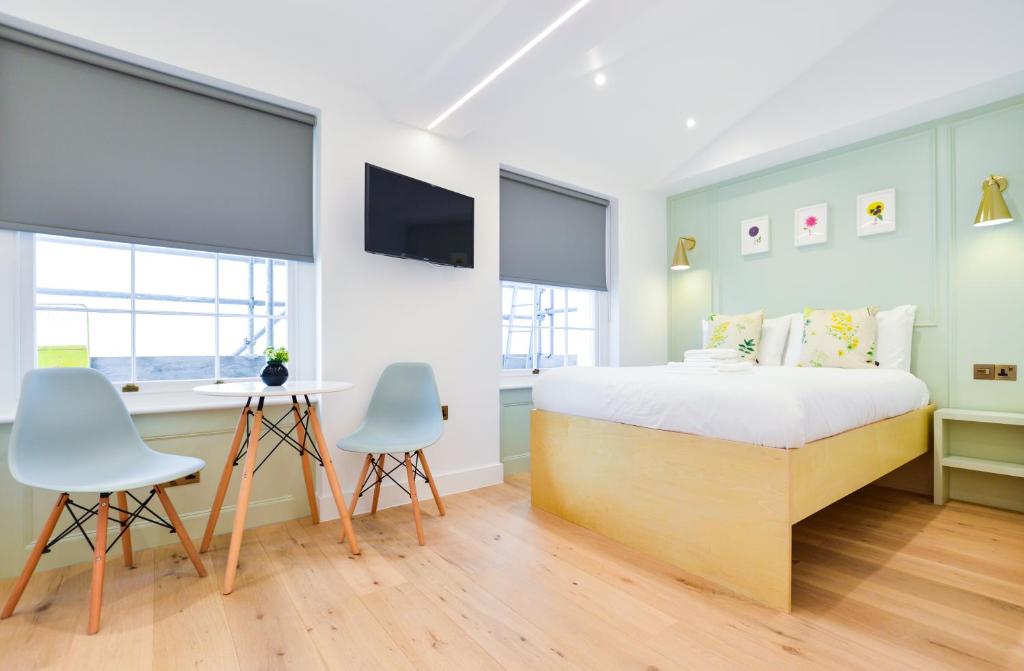 1 Schlafzimmer mit einem Bett, 2 Stühlen und einem Schreibtisch in der Unterkunft Star Street Serviced Apartments by Concept Apartments in London