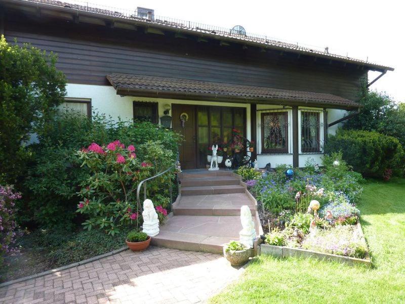 ein kleines Haus mit einer Veranda mit Blumen im Hof in der Unterkunft Haus Zaunwiese in Grasellenbach