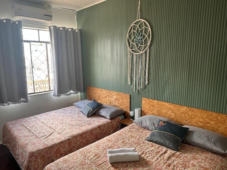 Quarto 6 no Centro de Itajaí, Ar+SmartTv في إيتاجاي: سريرين في غرفة بجدران خضراء
