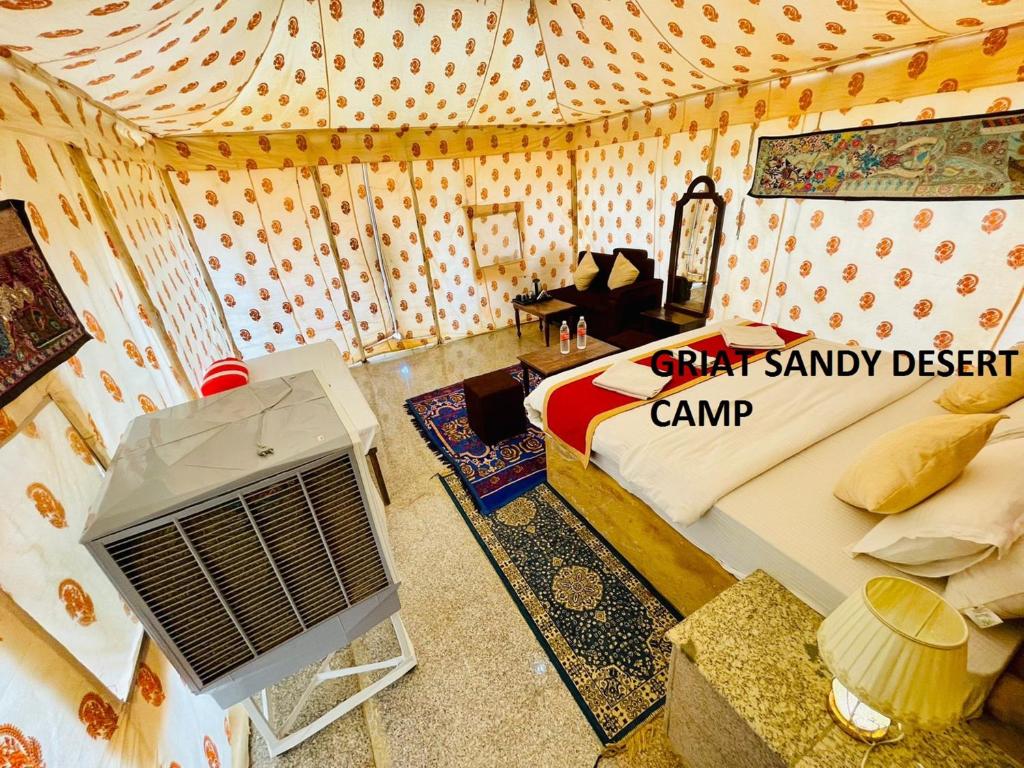 Griat sandy desert camp jaisalmer في جيلسامر: غرفة بها سرير وغرفة بها مروحة