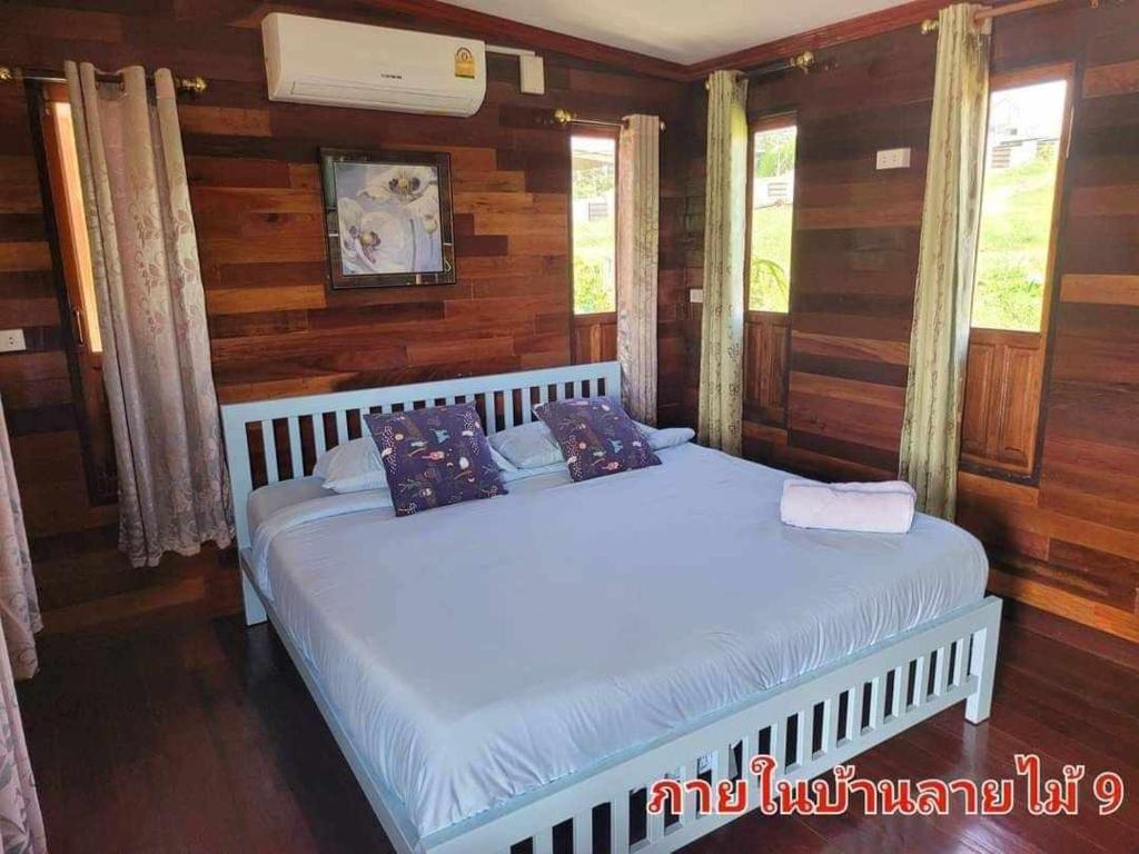 two beds in a bedroom with wooden walls and windows at The Memorize Resort in Ban Non Na Yao