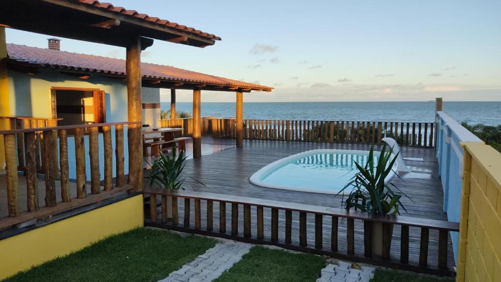 uma casa com um deque com piscina e oceano em Casa de Praia Recanto do Atlântico em Nova Viçosa
