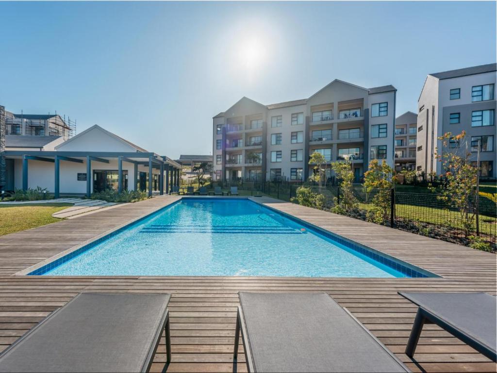 a swimming pool with benches next to some buildings at Ballito Village Luxury Apartments by DropInn in Ballito