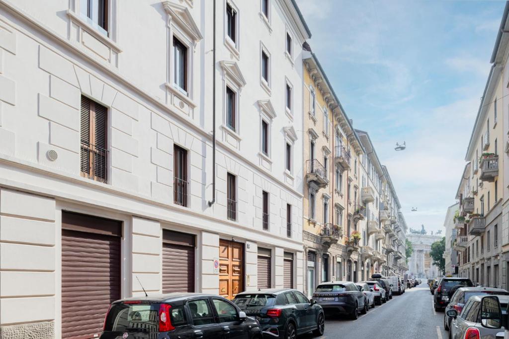 ulica miejska z zaparkowanymi samochodami i budynkami w obiekcie RELSTAY - Arco della Pace - Sunny Loft w Mediolanie