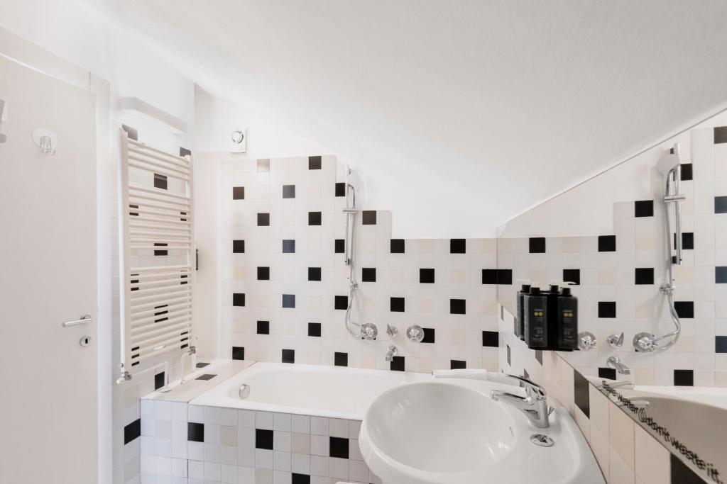 biała łazienka z umywalką i wanną w obiekcie RELSTAY - Arco della Pace - Sunny Loft w Mediolanie
