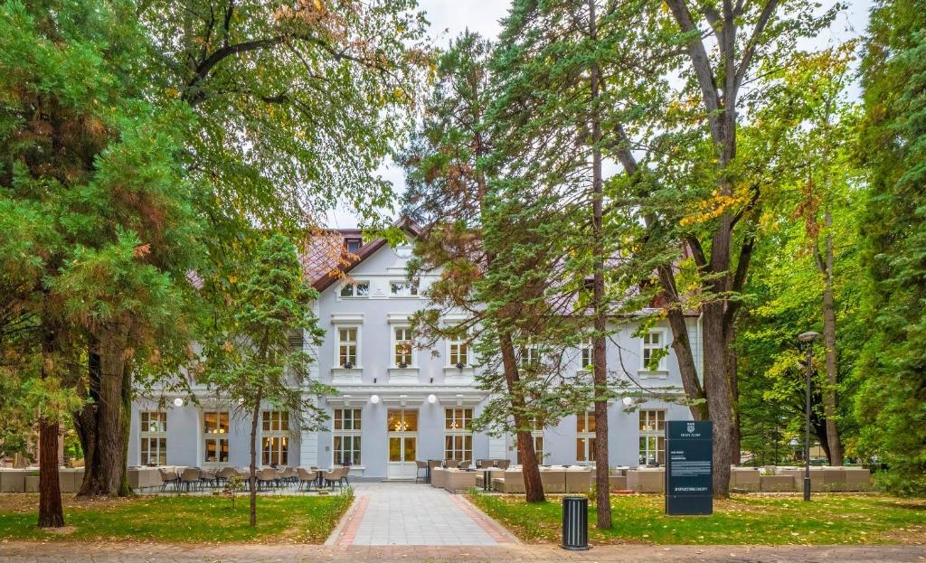 uma casa branca com árvores em frente em Hotel Podrinje em Banja Koviljača