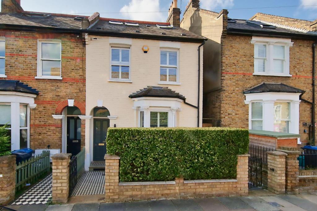 a house with a hedge in front of it at Family 4-Bed House & Secluded Garden - Wimbledon in London
