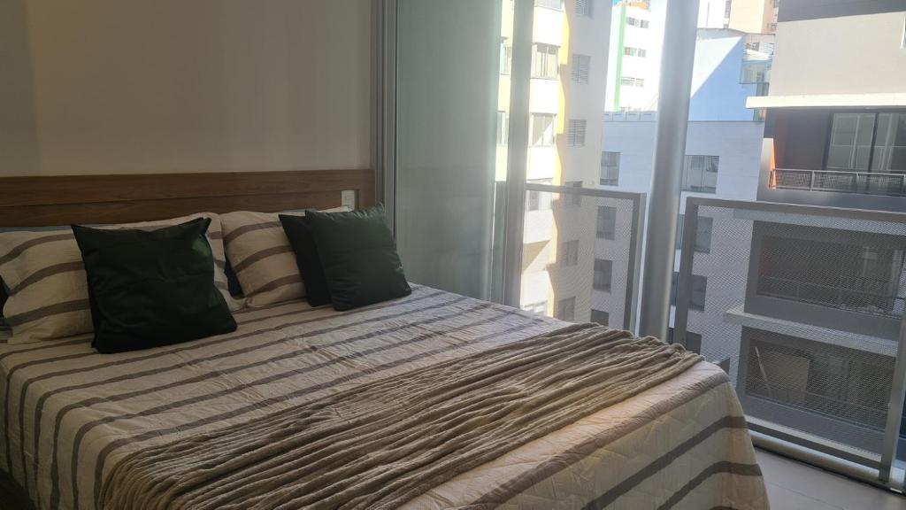 a bedroom with a bed with green pillows and a window at VN Frei Caneca in São Paulo