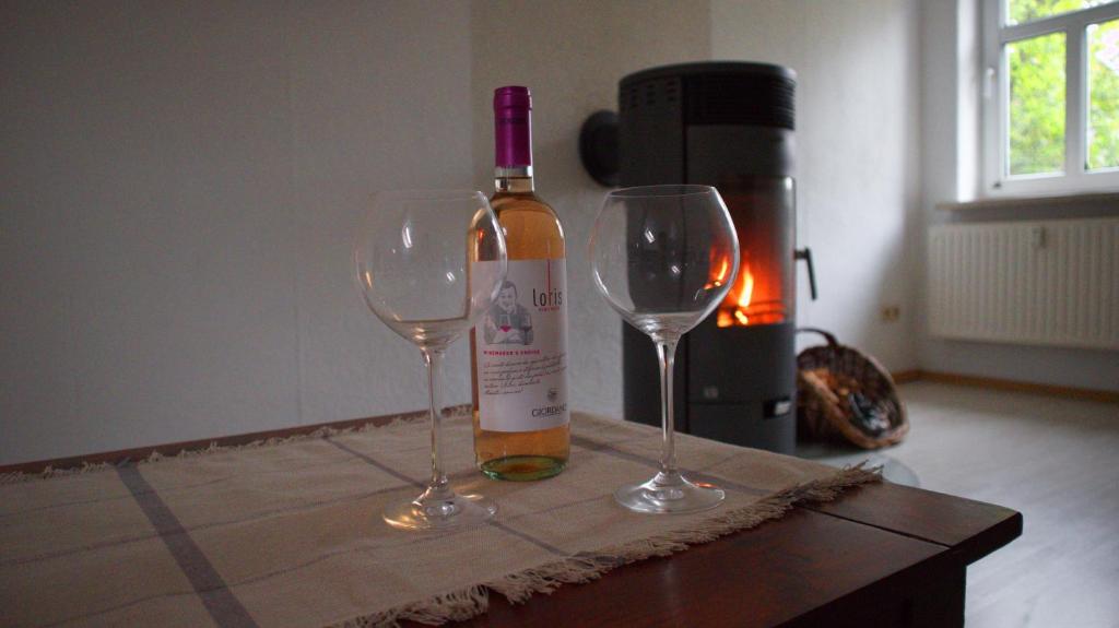 een fles wijn en twee wijnglazen op een tafel bij NOAH - Beste Lage, ruhig und romantisch in Zeulenroda