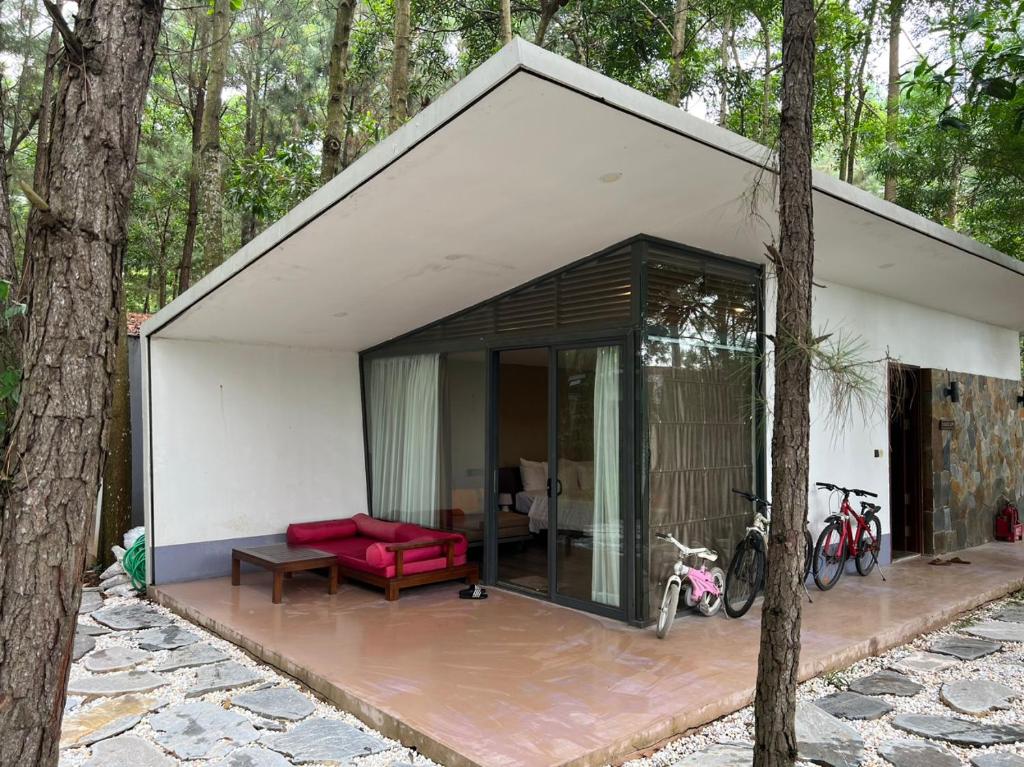 Phúc Yên的住宿－Forest Villa 329 Flamingo Dai Lai，森林中带红色沙发的白色小房子