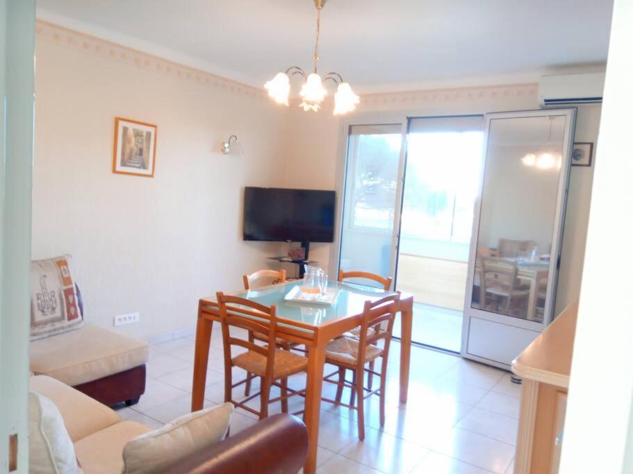 a living room with a table and chairs and a television at T3 tout confort en front de mer, clim in Saint-Cyprien