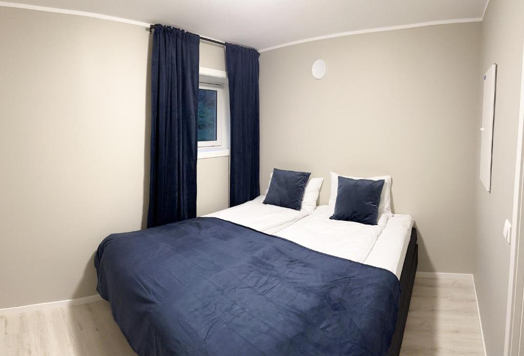 a bedroom with a large bed with blue sheets and a window at Tromsdalen Aurora Apartments in Tromsø