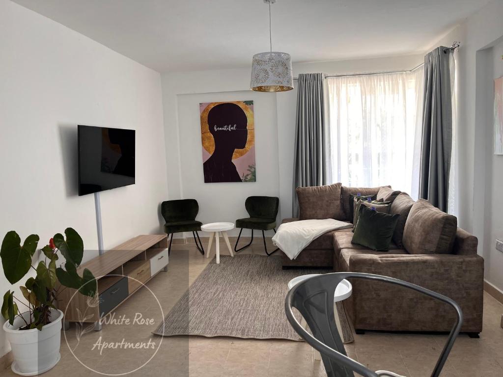 ein Wohnzimmer mit einem Sofa und einem Tisch in der Unterkunft WhiteRose Apartments in Meru