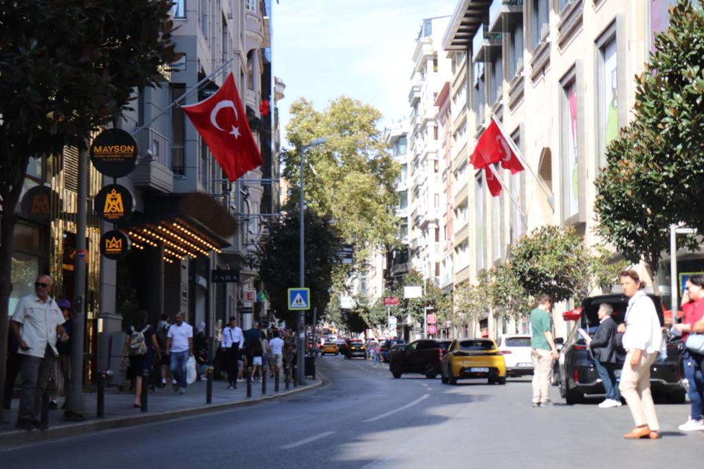 een drukke straat met mensen die lopen en vlaggen bij Mas Suites Nisantasi in Istanbul