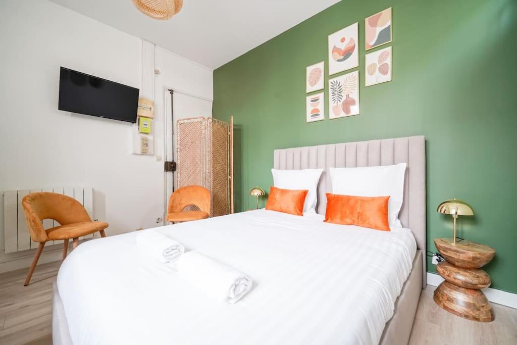 une chambre avec un grand lit blanc avec des oreillers orange dans l'établissement Green studio cosy and confortable - III, à Paris