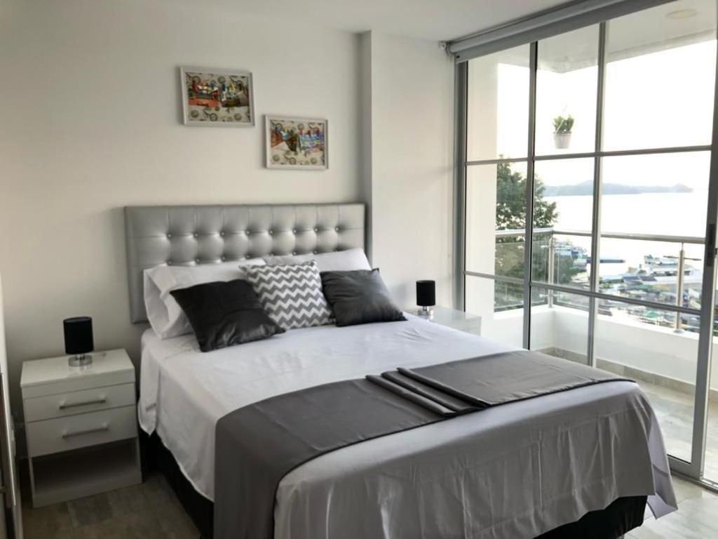 een slaapkamer met een groot bed en een groot raam bij Apartamentos View, calle del Malecón frente al lago in Guatapé