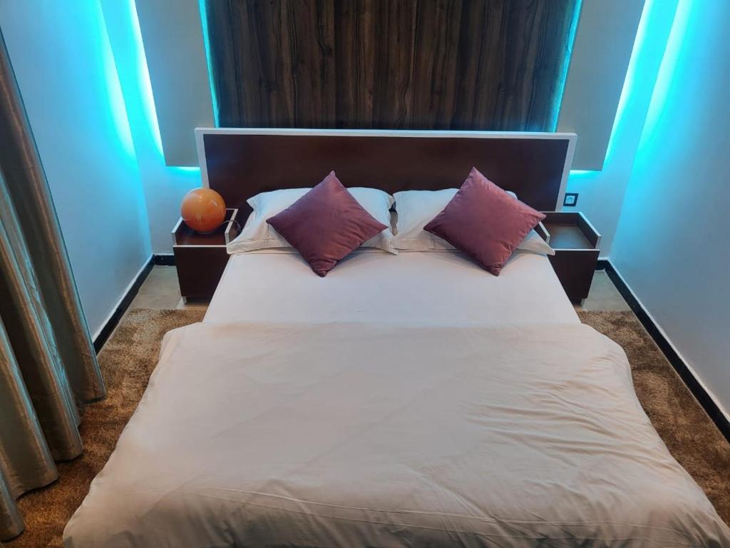 um quarto com uma grande cama branca com almofadas roxas em Sunset Views Sharifia Villa em Marrakech