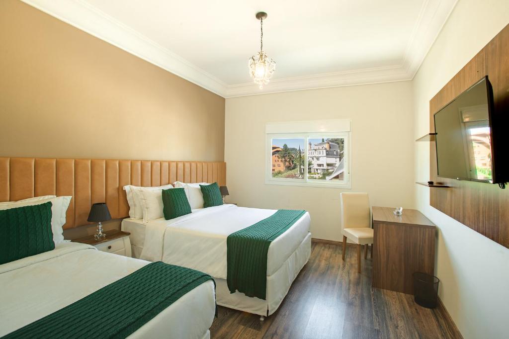 Cette chambre comprend deux lits et une télévision. dans l'établissement Altitude Lodge Hotel, à Campos do Jordão