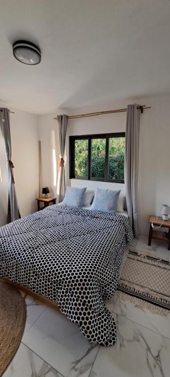 a bedroom with a black and white bed and a window at Résidence au bout du Morne in Le Morne