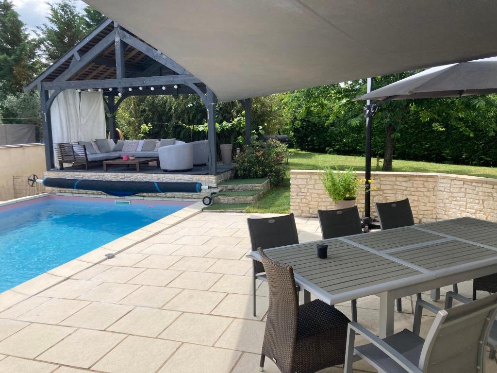 eine Terrasse mit einem Tisch, einem Sonnenschirm und einem Pool in der Unterkunft Maison de vacances in Chambray-lès-Tours