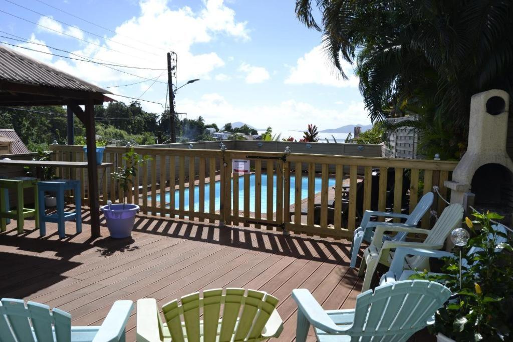 a deck with chairs and a table and a fence at Bungalow Caraïbes, proche de la route mais calme la nuit. in Trois-Rivières
