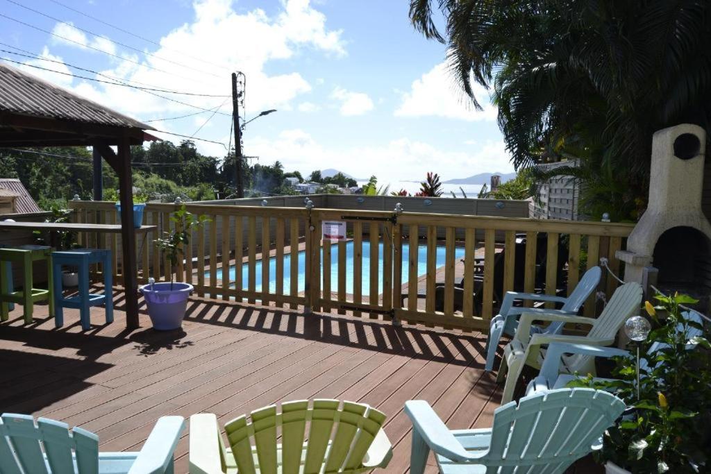 a deck with chairs and a table and a fence at Bungalows Caraibes et Goyave proches de la route mais calme la nuit in Trois-Rivières