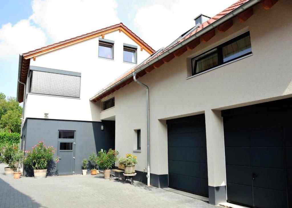 uma casa branca com duas portas de garagem e vasos de plantas em Weingut Edling em Roßdorf