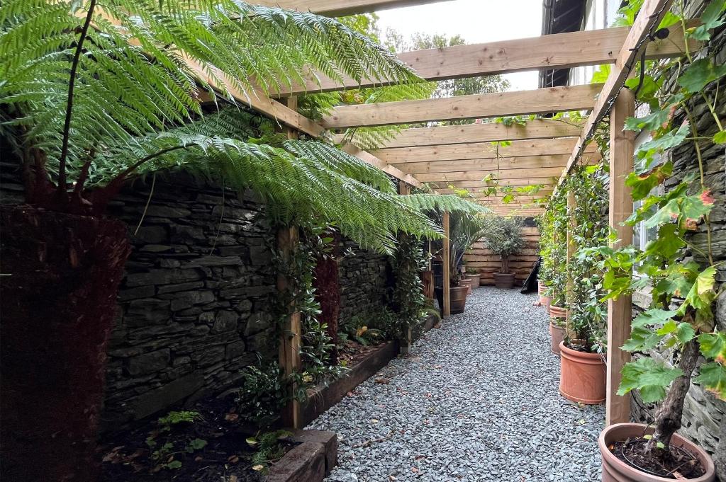 ein Garten mit Topfpflanzen und einer Holzpergola in der Unterkunft Quirky Retreats - The Hidden Retreat in Windermere