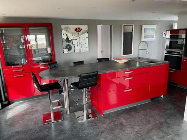 une cuisine avec des placards rouges et un comptoir dans l&#39;établissement Plage du Débarquement. Maison bord de Mer, à Saint-Côme-de-Fresné