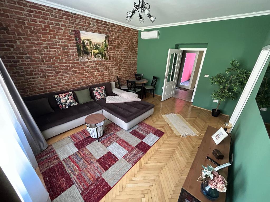 a living room with a couch and a brick wall at Asha Central Apartment in Timişoara