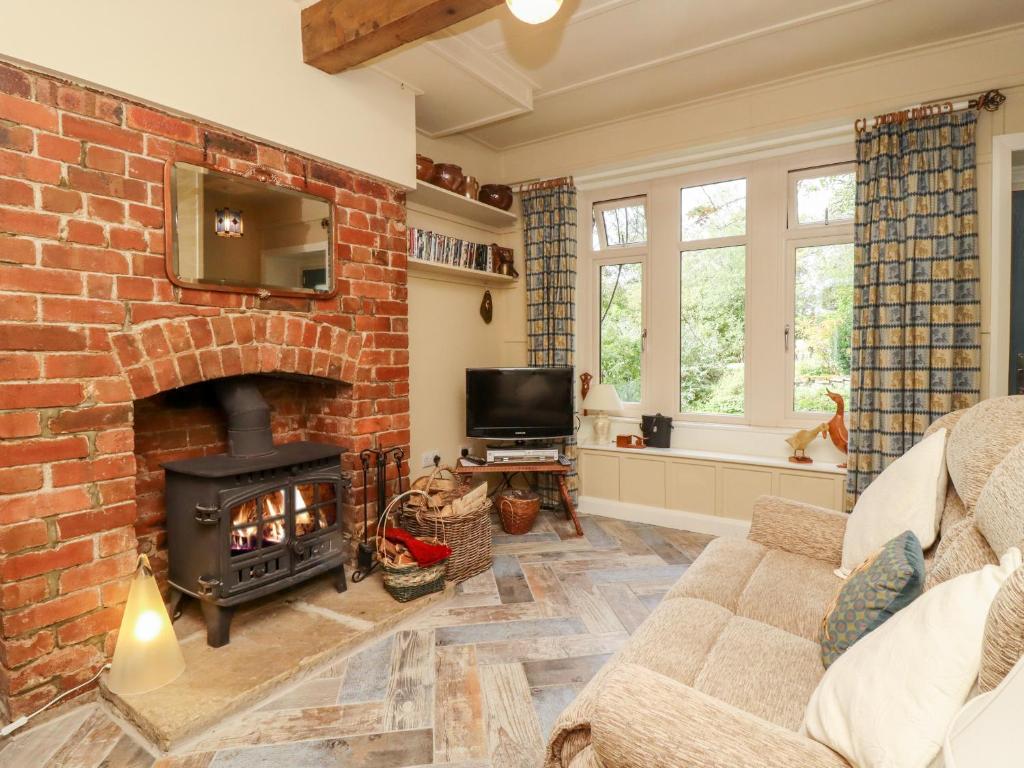 a living room with a brick fireplace and a tv at Oak Cottage in Skipton