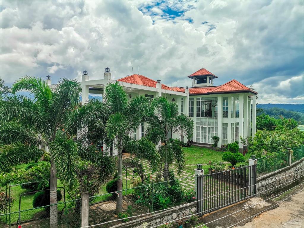 une grande maison blanche avec des palmiers devant elle dans l'établissement The Grove, à Kandy