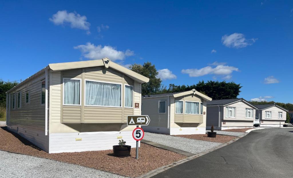 a row of mobile homes parked next to a street at Red Deer Village Holiday Park - 3 Bedroom, Self-Catering Holiday Home in Steps