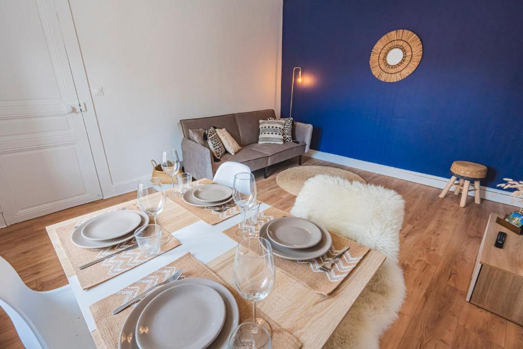 une salle à manger avec une table avec des assiettes et des verres à vin dans l'établissement 2 chambres - Centre Gare, à Reims