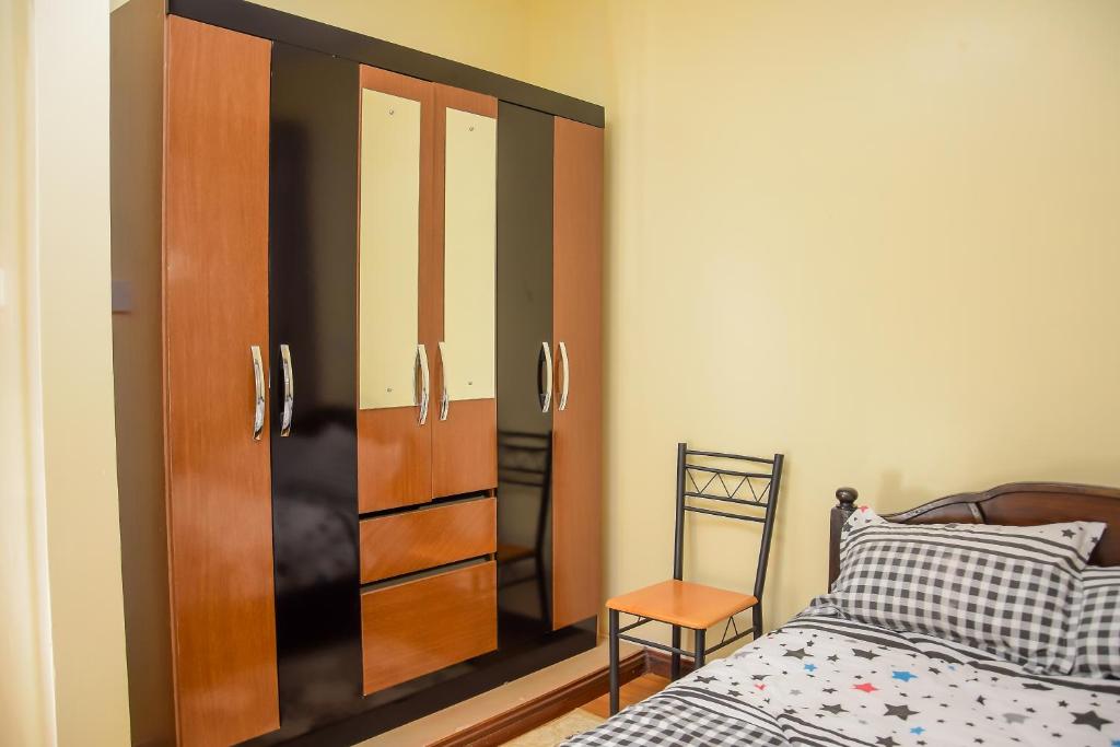 - une chambre avec un lit et une armoire en bois dans l'établissement The Penthouse Suites Serviced Apartments Meru, à Meru