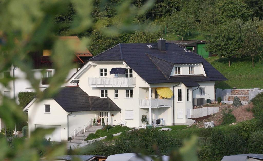 ein großes weißes Haus mit schwarzem Dach in der Unterkunft Ferienwohnung Am Spechtbach in Wald-Michelbach