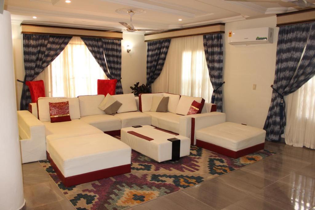 a living room with white couches and a rug at FREDA'S COURT in Accra