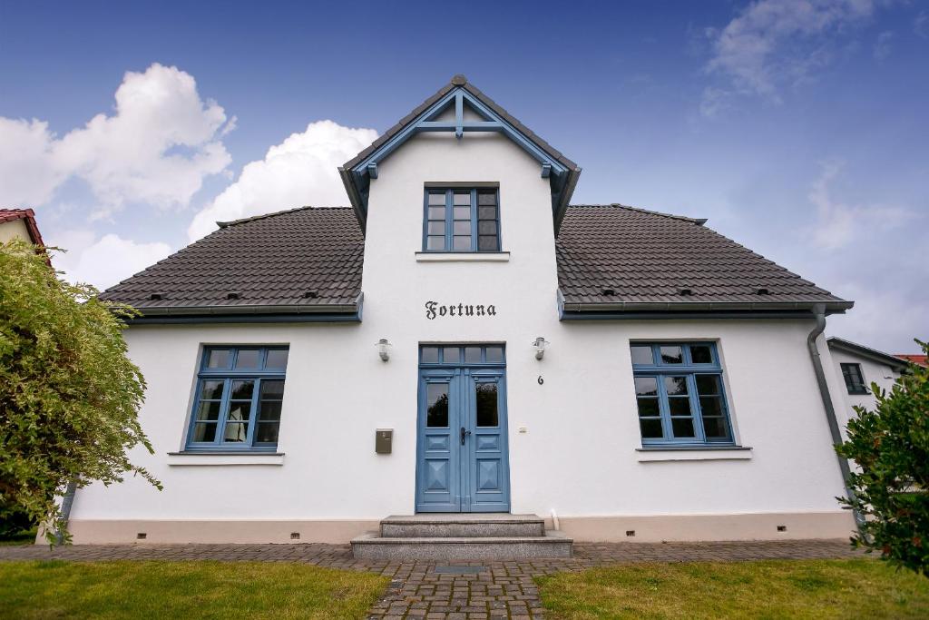 a white house with a blue door at Ferienwohnung Fortuna II in Thiessow