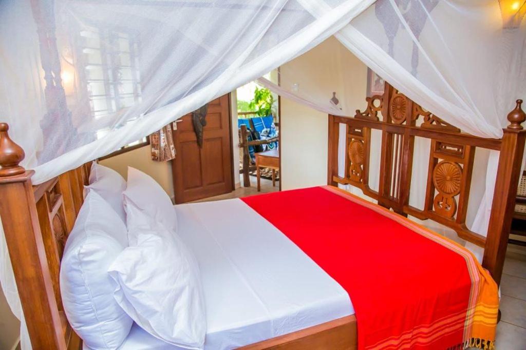 1 dormitorio con 1 cama con edredón rojo y blanco en Room Sawa, en Diani Beach