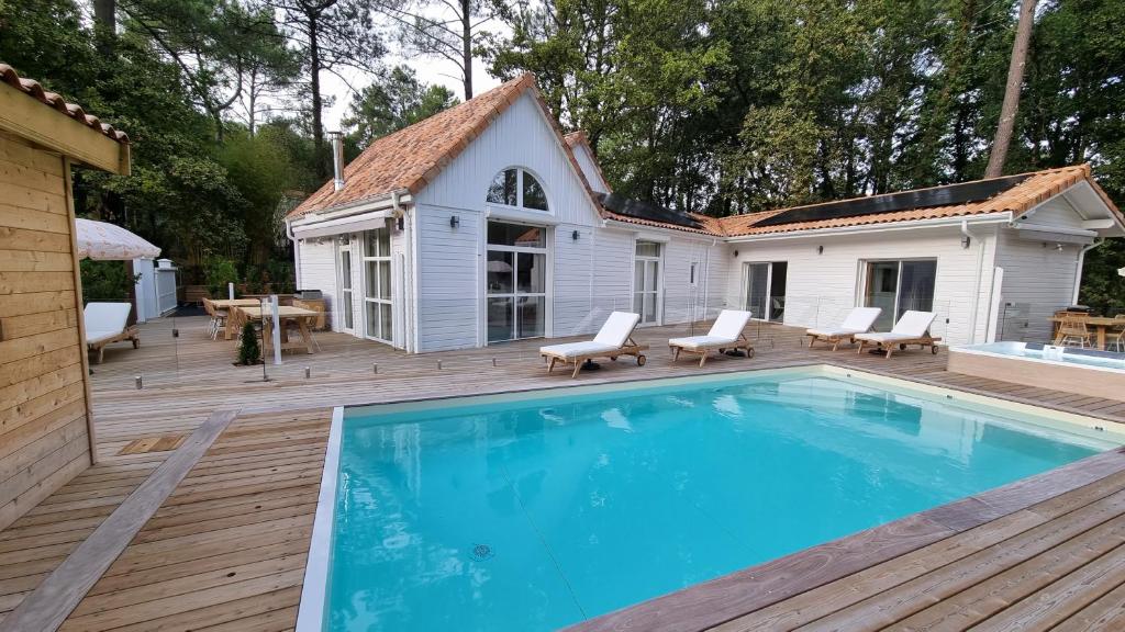 une maison avec une grande piscine sur une terrasse en bois dans l'établissement Les Chalets du Golf de Biscarrosse, à Biscarrosse