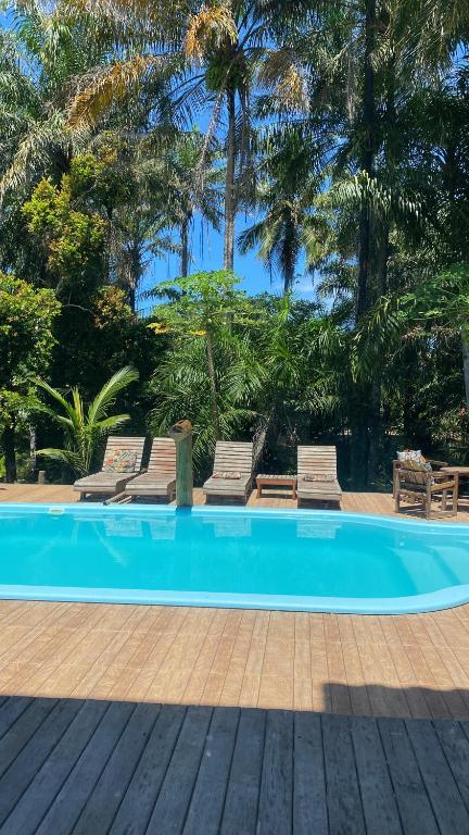 una piscina con 2 tumbonas y palmeras en Aconchego dos Netos 2, en Maraú