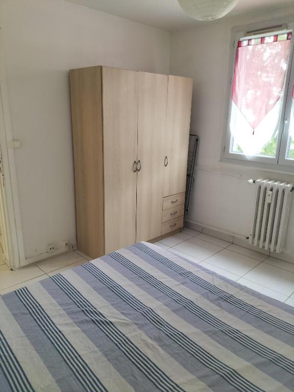 a bedroom with a bed and a cabinet and a window at Joli appartement proche métro in Lyon