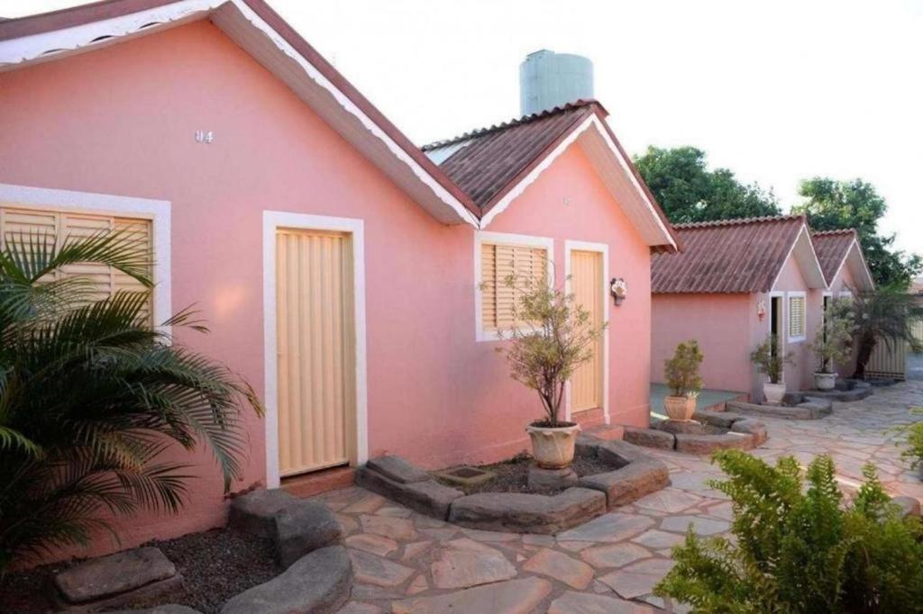 uma casa cor-de-rosa com algumas plantas à frente. em Pousada Caldas Novas em Caldas Novas