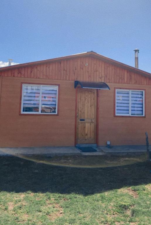 um edifício vermelho com uma porta e duas janelas em Ebenzer Comidas y Cabañas em Cochrane