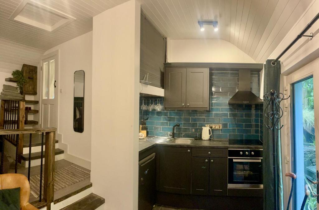 a kitchen with black cabinets and blue tiles at Railway cottage Annascaul in Anascaul