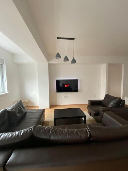 a living room with a black leather couch and a tv at Apartment in Skopje in Skopje