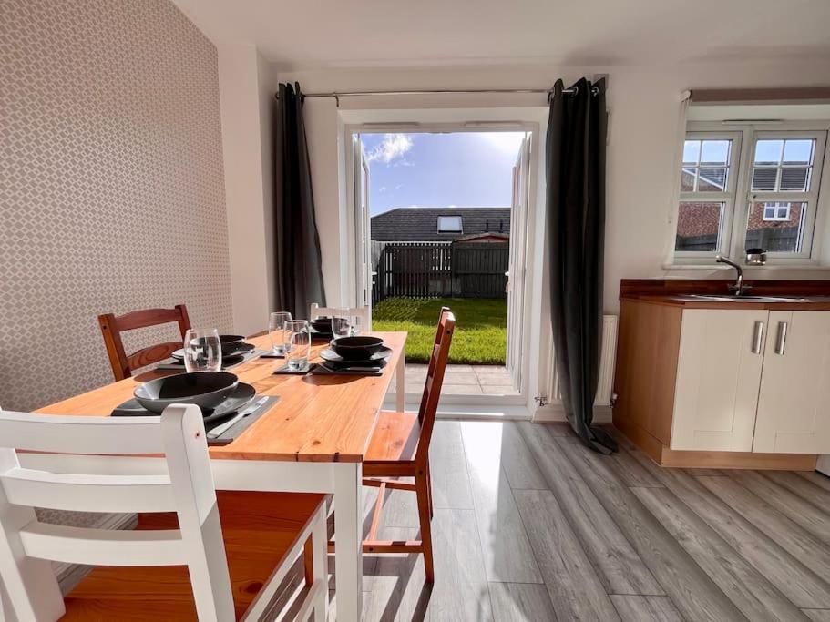 a dining room with a wooden table and a kitchen at Coral House by Blue Skies Stays in Thornaby on Tees