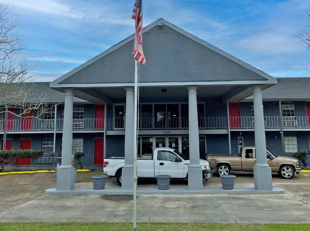 a building with a flag and a truck in front of it at Red Carpet Inn - Houma in Houma